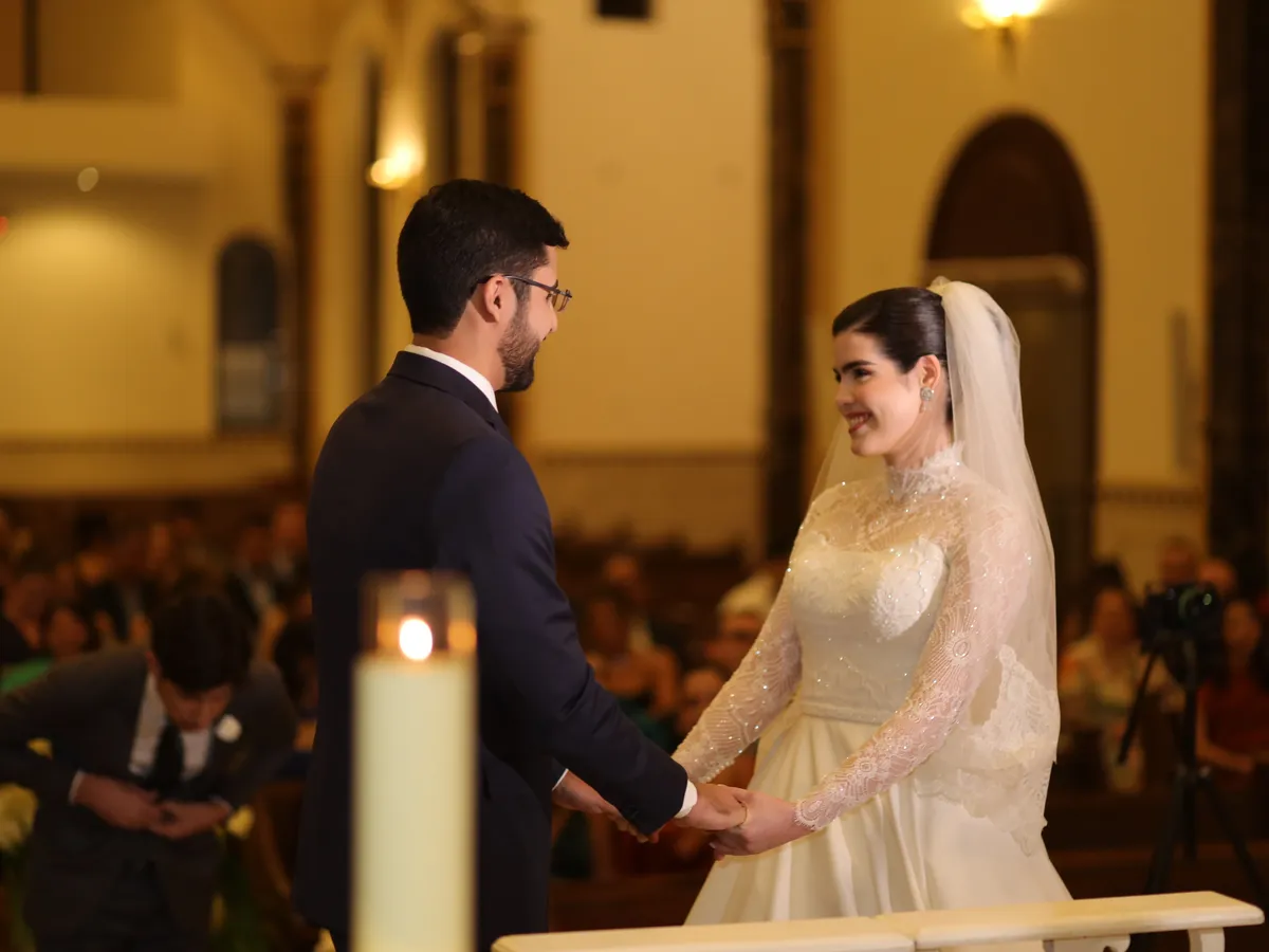 Cerimônia de casamento na igreja, com os noivos de mãos dadas diante dos convidados